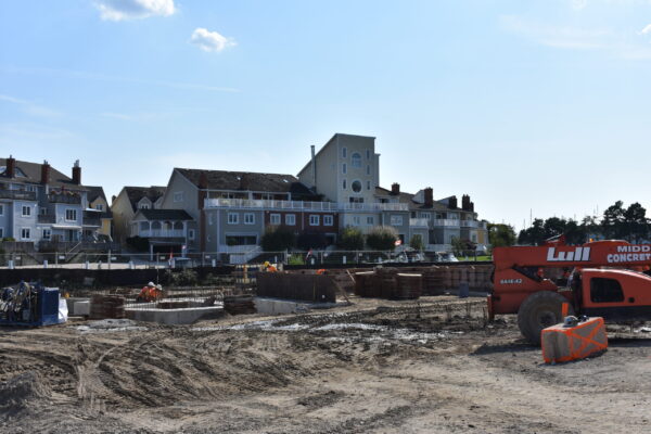 Venetian Boulevard Condominium building in the construction phase. The foreground shows heavy equipment and workers working on foundation for a new building, while another completed building stands in the background, a tall colourful condominium building.